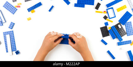 Close up of child's hands playing with colorful plastic bricks at the table Stock Photo