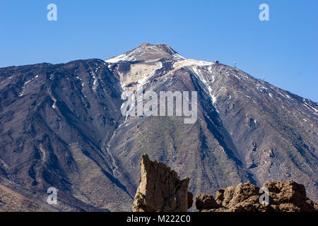 Mount Teide peak with volcanic rocks in the foreground.  The cable car is visible ascending  to the upper station.   Tenerife, Canary Islands 2016 Stock Photo