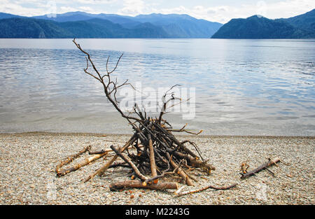 Prepared for a kindling fire on the shore of the Teletskoye Lake. The symbol of extreme secluded recreation in the wild Stock Photo