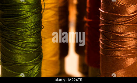 Spools of sewing thread in two rows going into perspective. Close-up shot Stock Photo