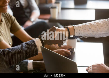 Multiracial men shaking hands in coffee house, close up view Stock Photo