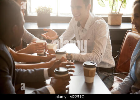 Multi ethnic group of friends drinking coffee together in cafe Stock Photo