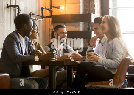Multiracial young friends having fun laughing drinking coffee in Stock Photo