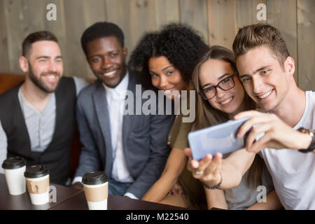 Young man taking selfie on smartphone at meeting with friends Stock Photo