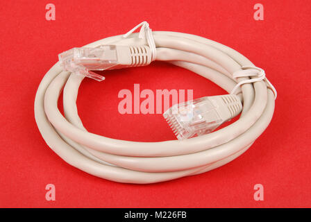 Patch cord grey network cable with molded RJ45 plug, isolated on a red background Stock Photo