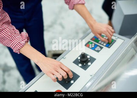 High angle close up of female hands pressing buttons on electronic control panel of modern machine unit at factory Stock Photo