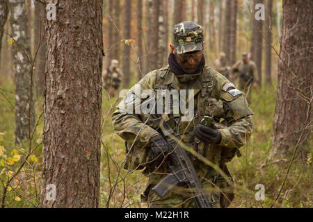 Soldier Using Compass A soldier uses a compass to navigate through the woods during a field ...