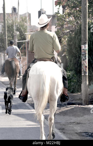 A man on a horse riding on a street in Michaocan, Mexico. Stock Photo