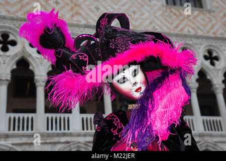 Cat costume - Female Venetian Mask in pink / black elegant costume on St. Mark's Square in Venice with traditional venetian pillar - Venice Carnival Stock Photo