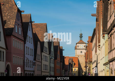 Colorful building and clock tower in old street of Rothenburg ob der Tauber, Bavaria, Germany with bright clear blue sky. Stock Photo