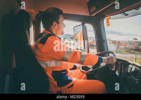 Garbage removal worker driving a dump truck  Stock Photo