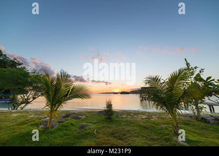 Togean Islands Sunrise, Togian Islands travel destination, Sulawesi, Indonesia. Beach with palm and transparent turquoise water with scattered islets. Stock Photo