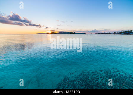 Togean Islands Sunrise, Togian Islands travel destination, Sulawesi, Indonesia. School of fish in transparent turquoise water with scattered islets. Stock Photo