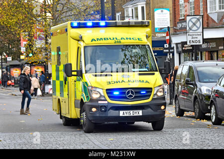 East of England blue light Emergency Ambulance Service NHS vehicle & crew on 999 journey pedestrians crossing High Street Brentwood Essex England UK Stock Photo