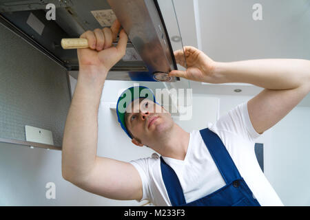 Handsome foreman fixing exhaust hood in the kitchen. Stock Photo