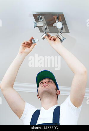 Handsome male electrician changing the light bulb. Stock Photo