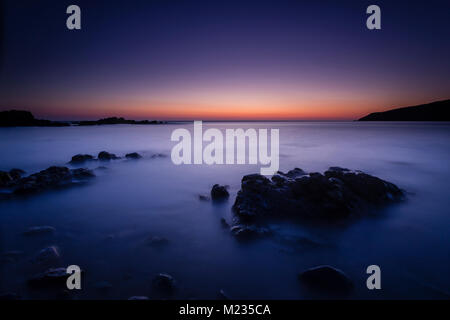 Calm sea and rocks at dusk on the coast of Anglesey, North Wales Stock Photo