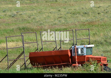 Old abandoned farm equipment sits in a farmers field rusting away Stock Photo