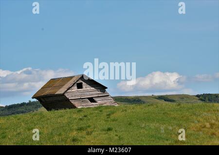 A old abandoned grain shed sits in a farmers field slightly leaning to one side and ready to fall over Stock Photo