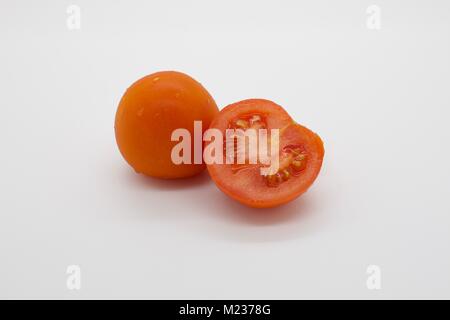 One whole tomato and a half on a white background Stock Photo