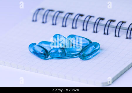 Blue pills in capsule shape scattered on a white sheet. Blue pills isolated on an light background Stock Photo