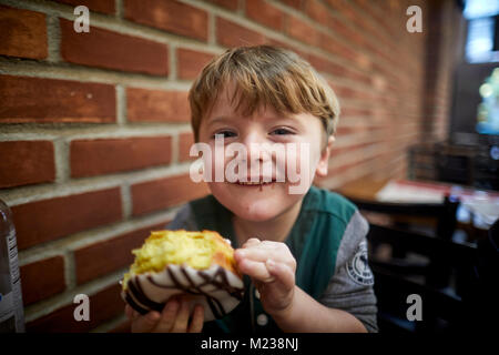 New York City Manhattan, 8th Avenue boy eating large donut cake Stock Photo