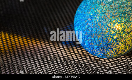 Abstract background with detail of a ball covered by netting from fibers. Texture from black hexagonal grid and glowing blue sphere with copy space. Stock Photo