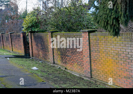 Tilting red brick garden wall, probably caused by subsidence Stock Photo