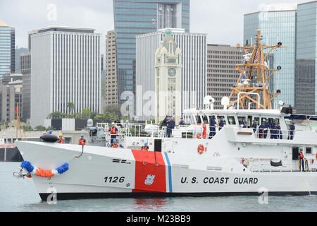 The Coast Guard Cutter Joseph Gerczak (WPC 1126) passes by Aloha Tower in Honolulu Harbor while en route to Coast Guard Base Honolulu, Feb. 4, 2018. The Joseph Gerczak is the second of three 154-foot fast response cutters stationed in Hawaii. (U.S. Coast Guard photo by Petty Officer 2nd Class Tara Molle/Released) Stock Photo