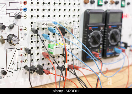 electricity, equipment, science concept. close up of wires in different coloures that connect this electric device and two multimeters with small scre Stock Photo