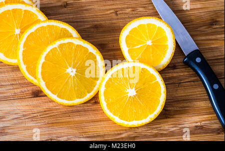 Orange slices on wooden kitchen board with cooking knife Stock Photo