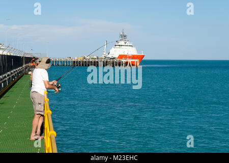 Man fishing from pier and commercial fishing boat Go Phoenix in port,  Broome, West Kimberley, Western Australia Stock Photo