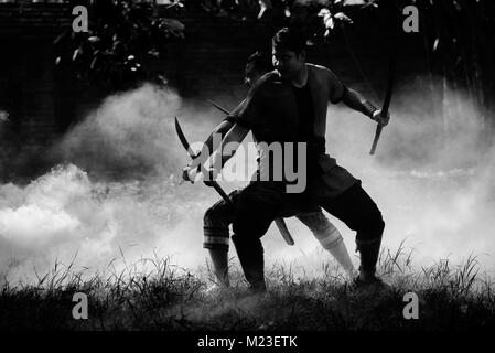 AYUTTHAYA, THAILAND - DECEMBER 17: Two ancient swordmen  be ambush alert in the smoke of war fire make more shadow and Silhouette and prepare for atta Stock Photo