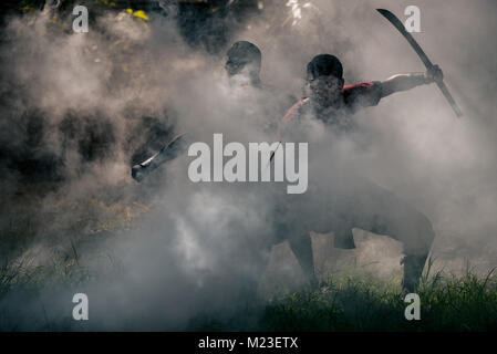 AYUTTHAYA, THAILAND - DECEMBER 17: Two ancient swordmen  be ambush alert in the smoke of war fire make more shadow and Silhouette and prepare for atta Stock Photo