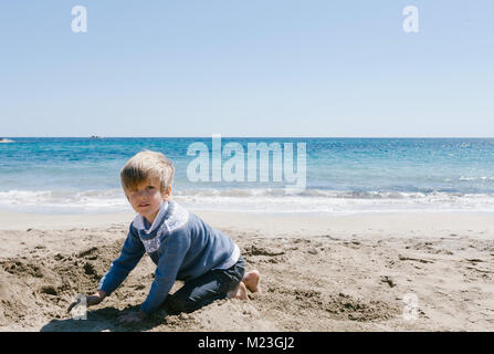 blond boy with blue eyes playing on the beach in winter Stock Photo