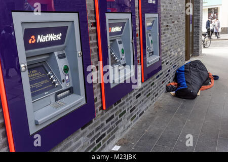 Person sleeping rough next to Natwest ATM cash machines in London, England, United Kingdom, UK Stock Photo