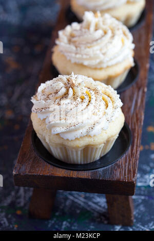 Homemade vanilla cupcakes with lemon cream cap on a dark background. Selective focus. Stock Photo