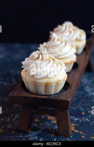 Homemade vanilla cupcakes with lemon cream cap on a dark background. Selective focus. Stock Photo