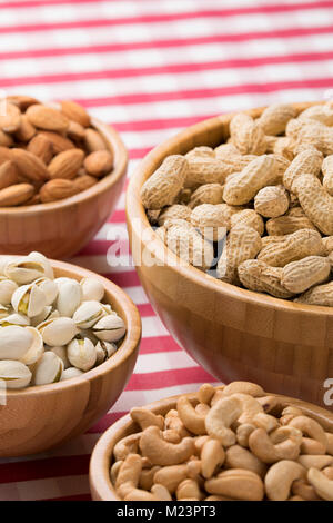 Close up of party bowls of peanuts, almonds, pistachios, and cashews on a red checkered tablecloth Stock Photo