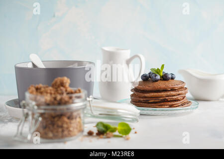 Chocolate pancakes, chocolate baked granola in a jar and milk. Healthy breakfast concept. Stock Photo