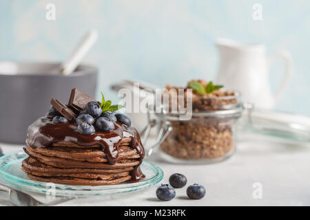 Chocolate pancakes with syrup and berries, chocolate granola, milk and eggs. Breakfast concept Stock Photo