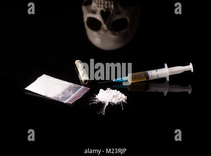 cocaine, Herion or other illegal drugs that are sniffed by means of a tube or injected with a syringe isolated on black glossy background Stock Photo