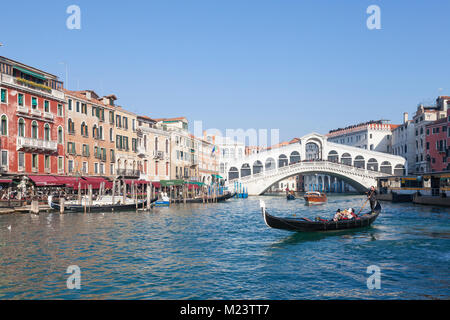 Gondola with tourists in front of the Rialto Bridge, Grand Canal, San Polo,  Venice, Italy on a sunny  blue sky winter day Stock Photo