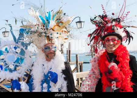 Venice, Veneto, Italy 4th February 2018. Two men in colourful historical costumes  and masks at the Venice Carnival on the Riva degli Schiavoni, San Marco, with lagoon backdrop. Stock Photo