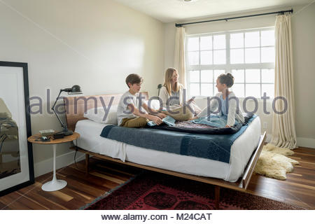 Mother and children folding laundry on bed