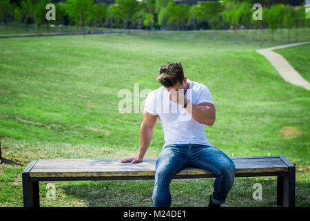 Man in city park crying on bench Stock Photo