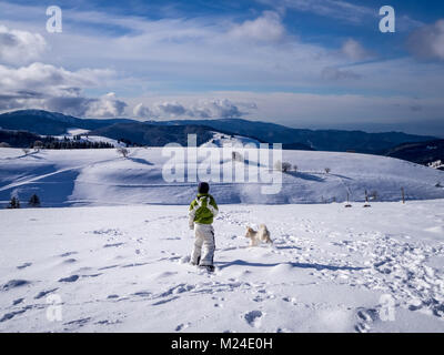 Kid playing with a dog and looking down the Rhine valley from a place called 'Schauinsland' which means look into the valley. Taken on a beautiful win Stock Photo