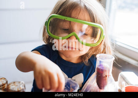 A 3-year old toddler girl works with science experiment equipment Stock Photo