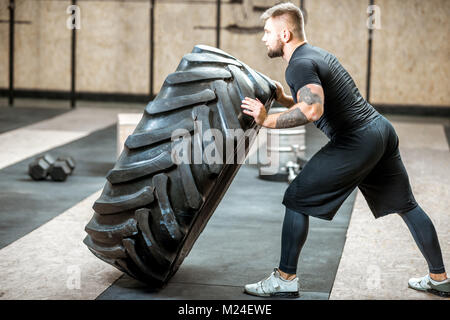 Man pushing a tire in the gym Stock Photo