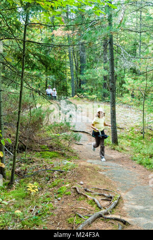 A granddaughter is running ahead of her sister and grandmother on a hike in the wilderness Stock Photo